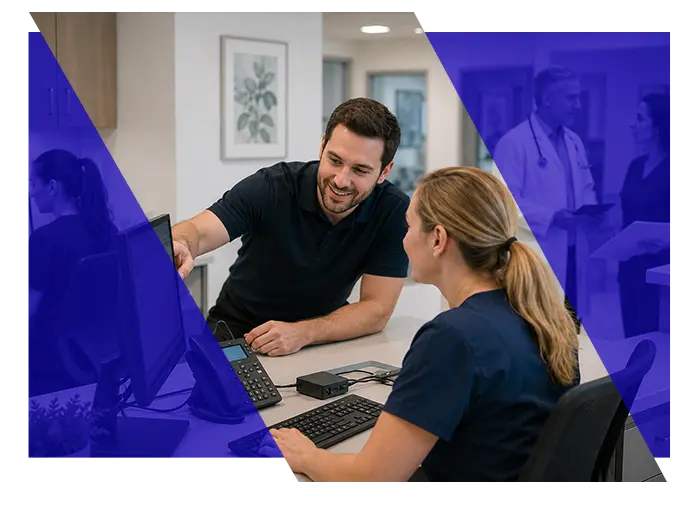 IT technician assisting a healthcare office employee at a computer