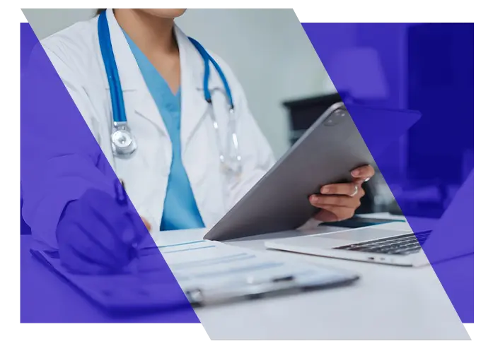 Healthcare professional reviewing information beside a laptop in a medical office
