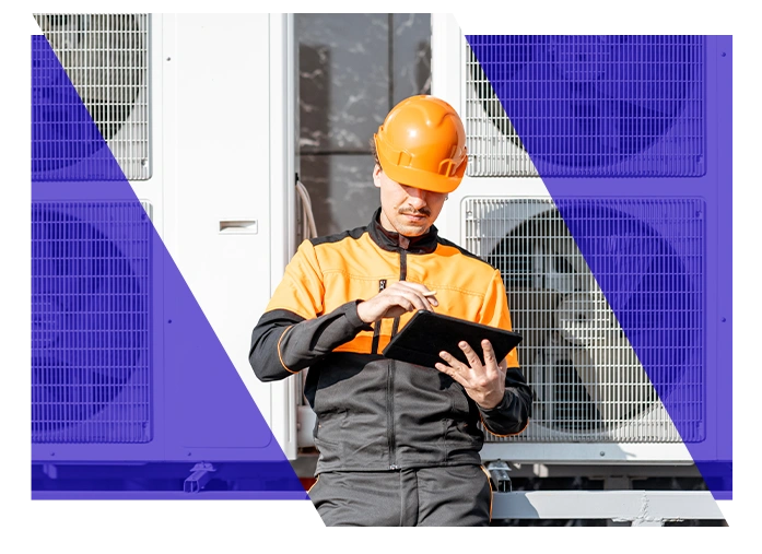 HVAC technician using a tablet beside commercial HVAC equipment