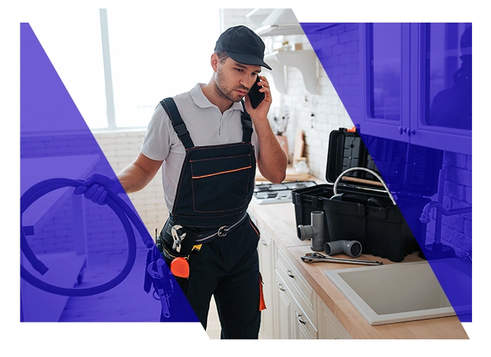 Plumbing technician speaking on a phone while working in a kitchen
