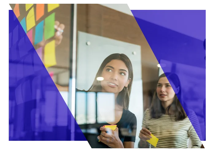 Project team members planning tasks with sticky notes on a glass board