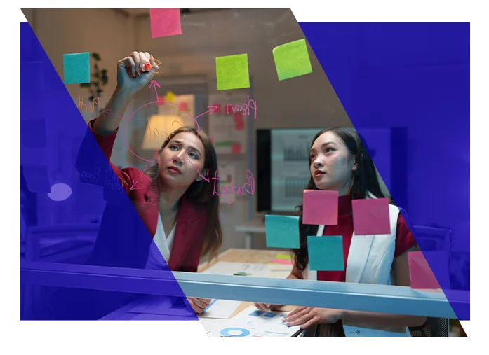 Project team members mapping tasks and notes on a glass planning board